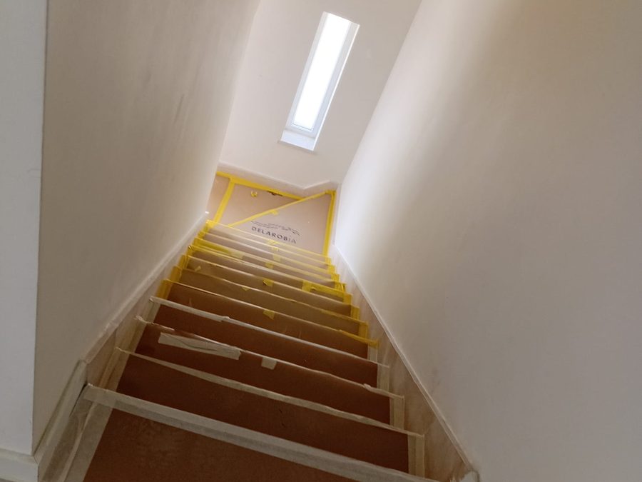 Interior staircase with the steps protected and a narrow high window