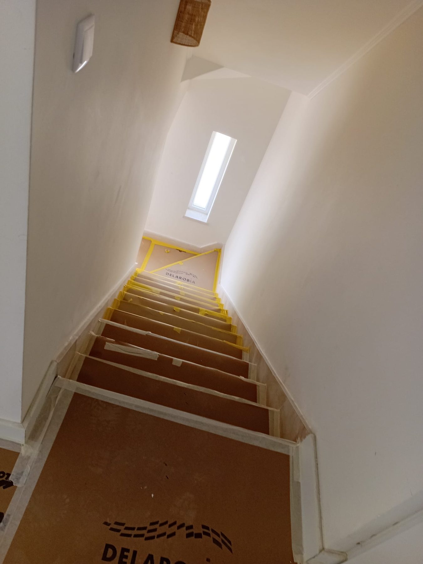 Interior staircase with the steps protected and a narrow high window