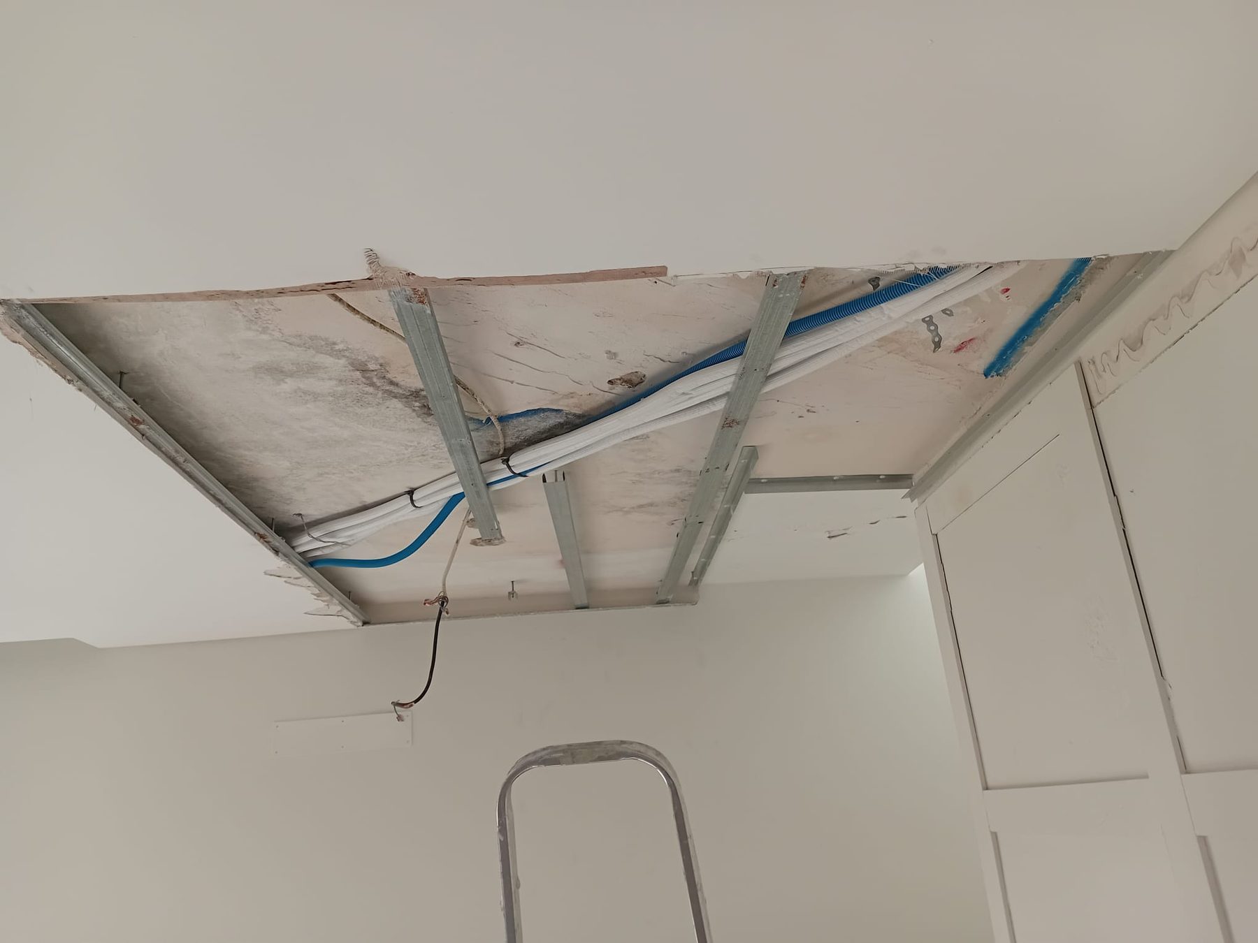 Teto aberto com a cablagem elétrica nova e a estrutura metálica à vista