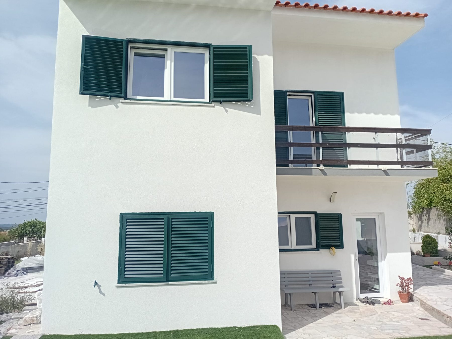 The same façade finished and painted white, with the green shutters