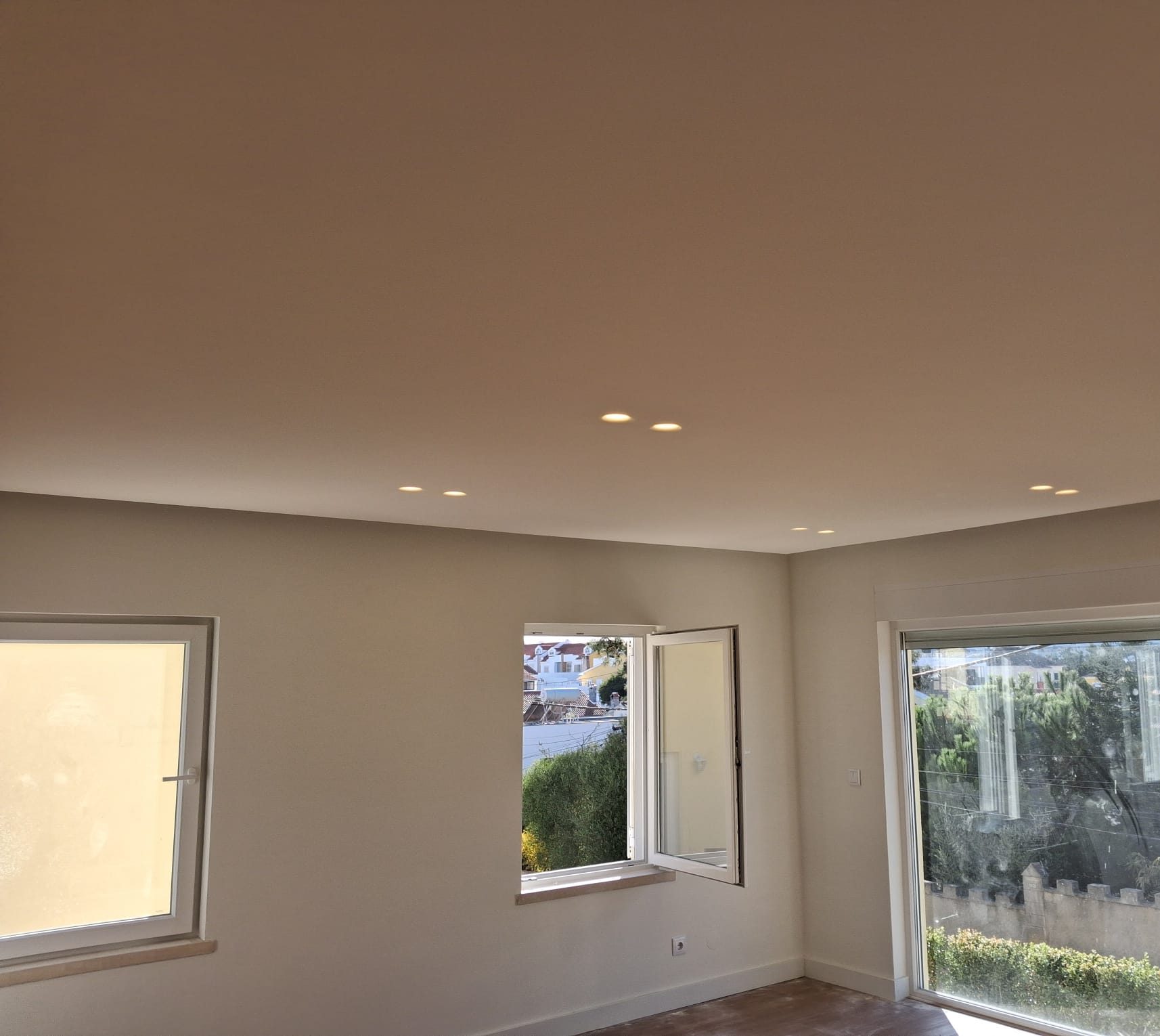 The same room clean and finished, with ceiling spotlights and the windows onto the garden