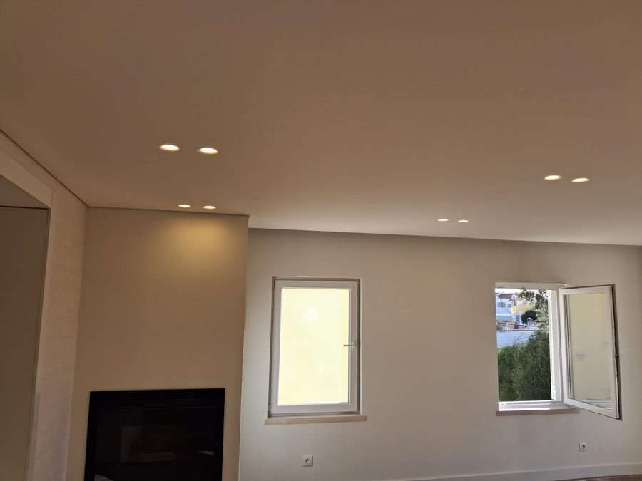 Finished living room with the fireplace, windows and recessed ceiling spotlights