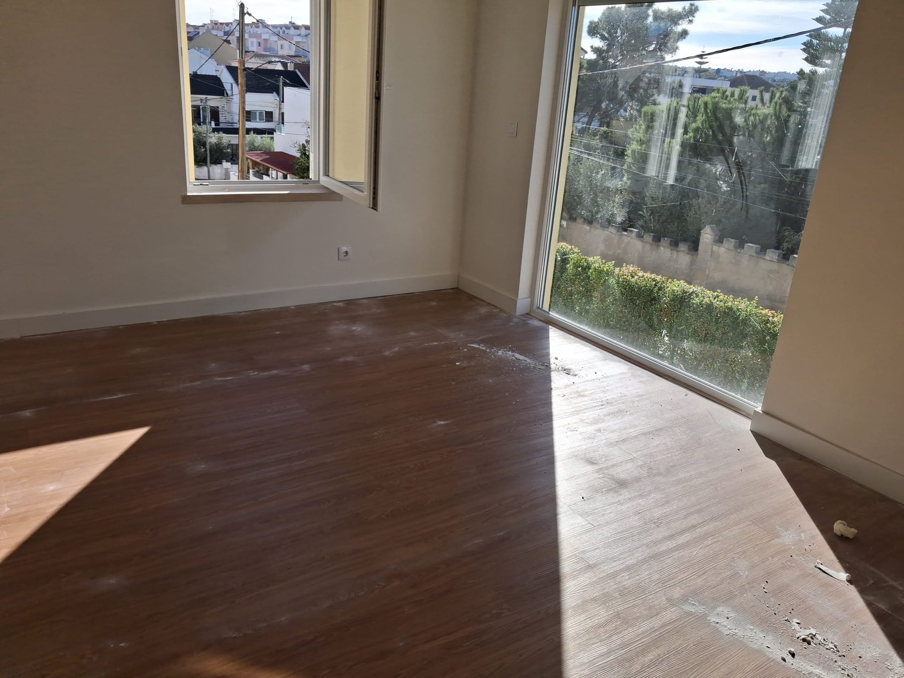 Living room with the new floor still covered in dust, an open window and the large window onto the garden