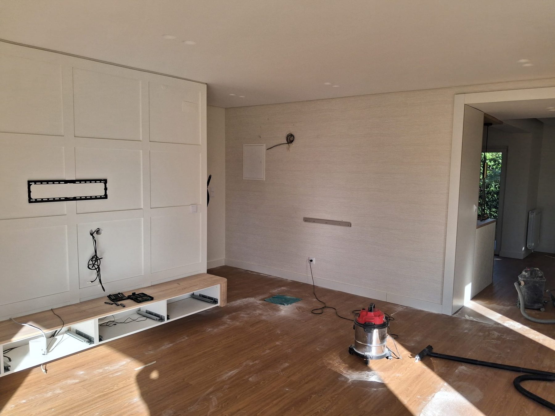 TV wall with the low cabinet, a dusty floor and a vacuum cleaner