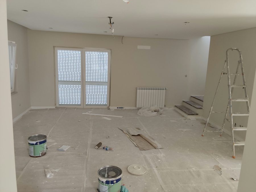 Empty room with the floor protected, paint tins and a stepladder