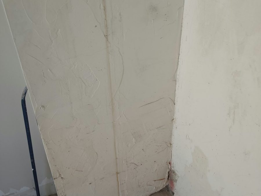 Corner with damaged plaster and an exposed pipe