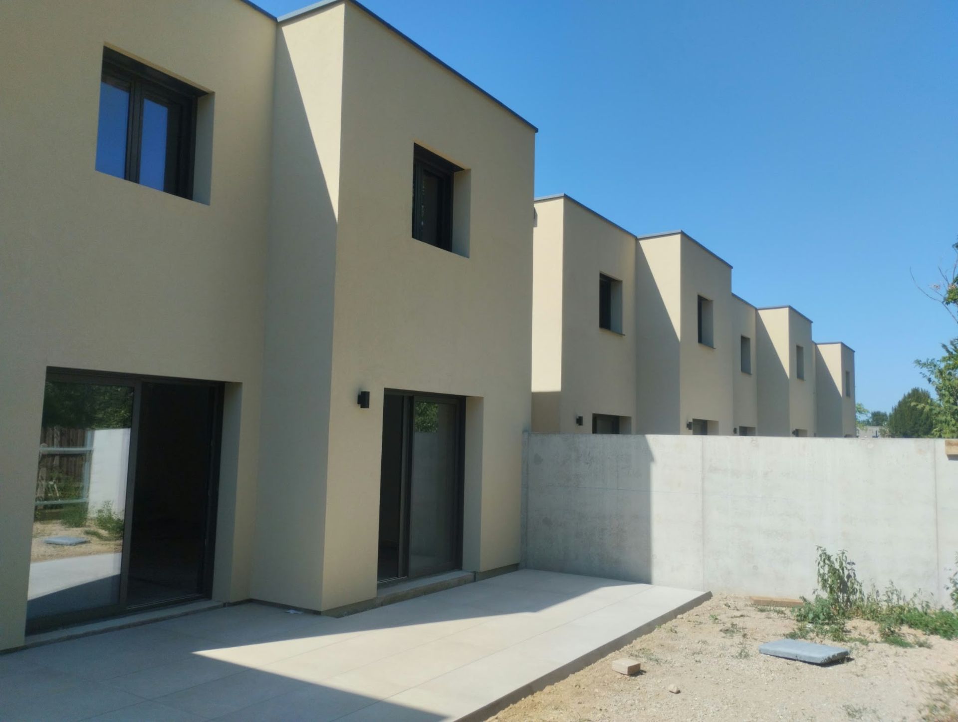 Finished terraced houses with clean lines, sand-coloured façades, dark window frames and a terrace
